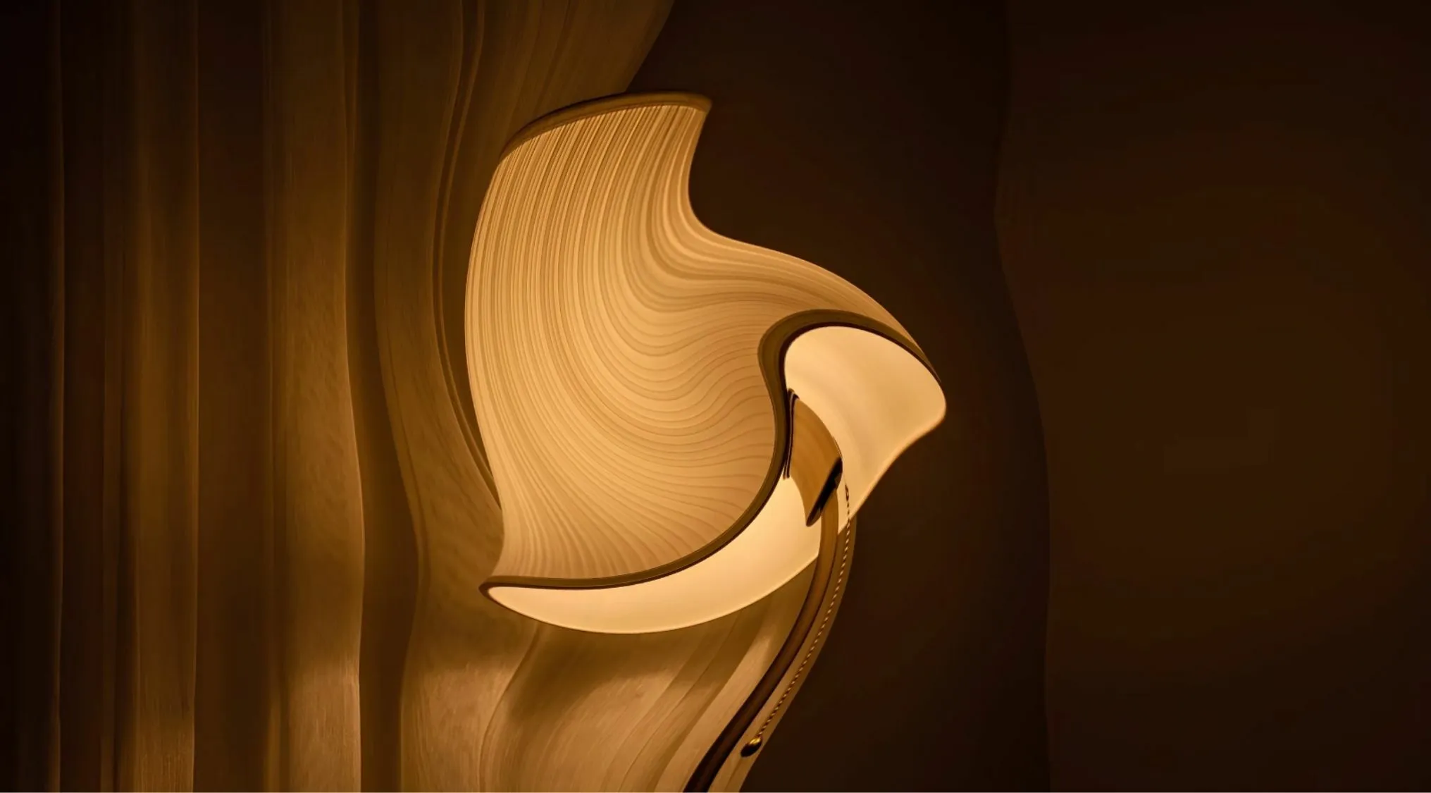 A distorted image of a unique, modern floor lamp with a wavy, glowing shade against a dark background.
