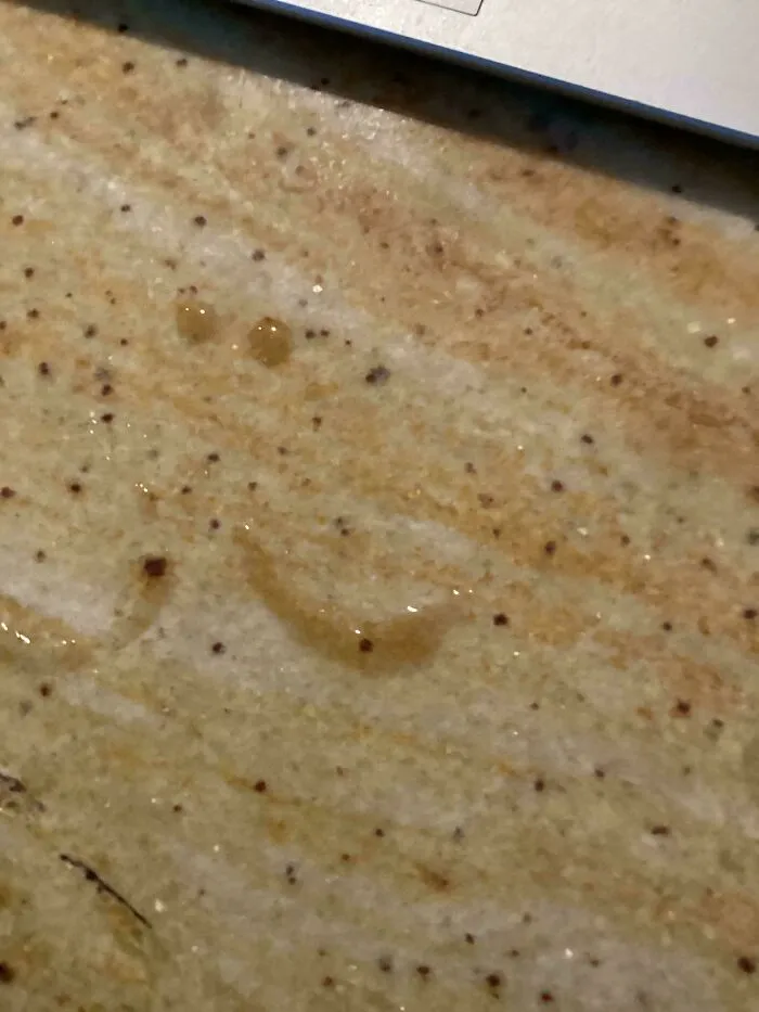 Wholesome images showing water droplets forming a smiley face on a speckled countertop.