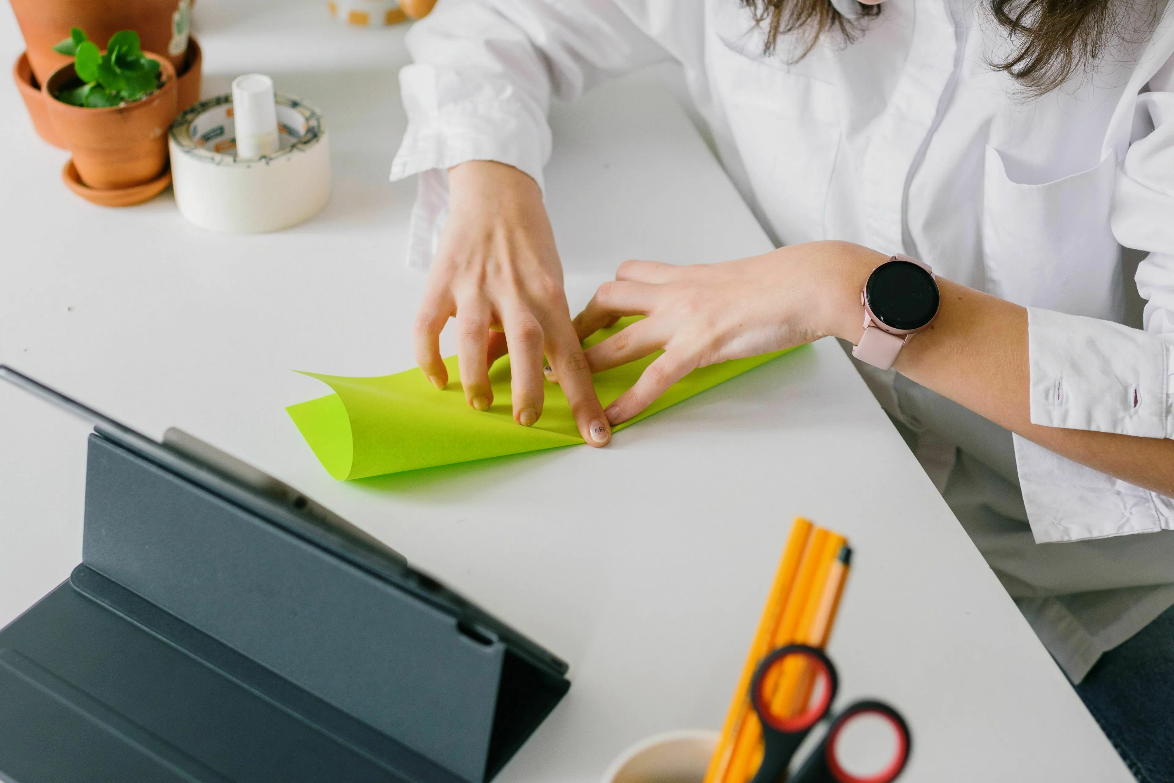 A person folding a sheet of paper in half, illustrating a math problem about layers of paper.