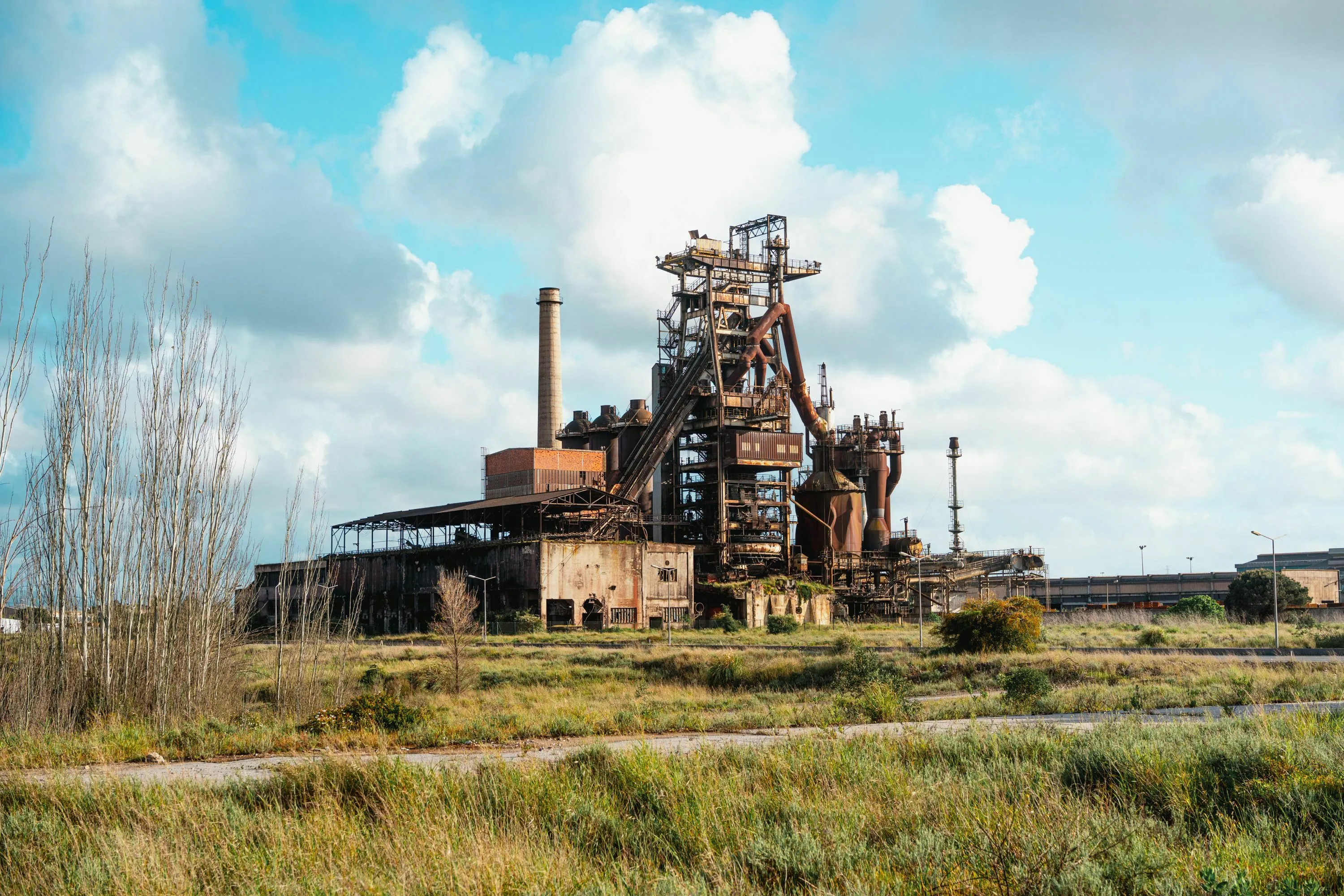 A sprawling, old industrial complex under a partly cloudy sky, representing the historical period of rapid manufacturing and technological growth.