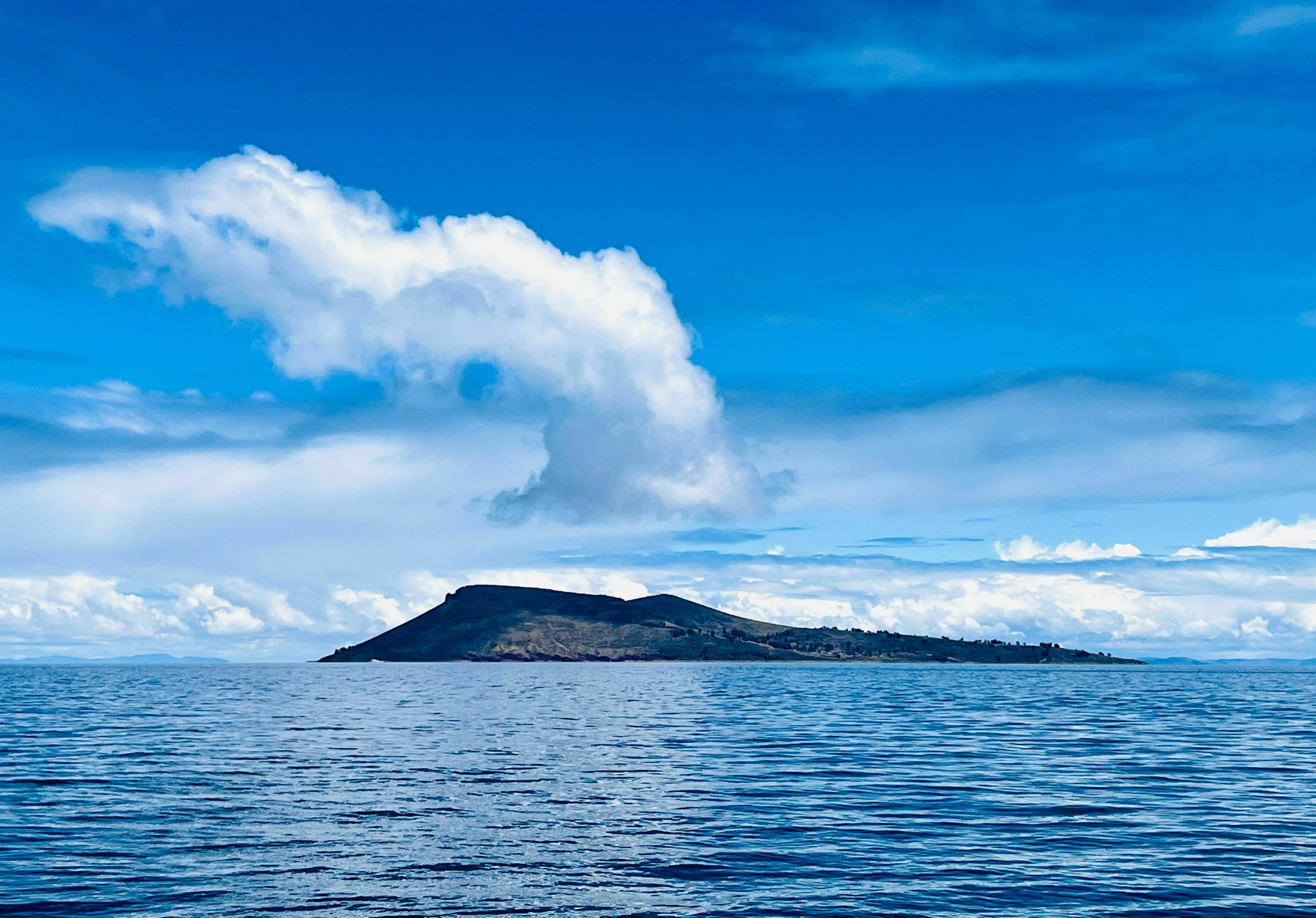 A beautiful landscape image of a large island in the world, with a clear blue sky and calm water.