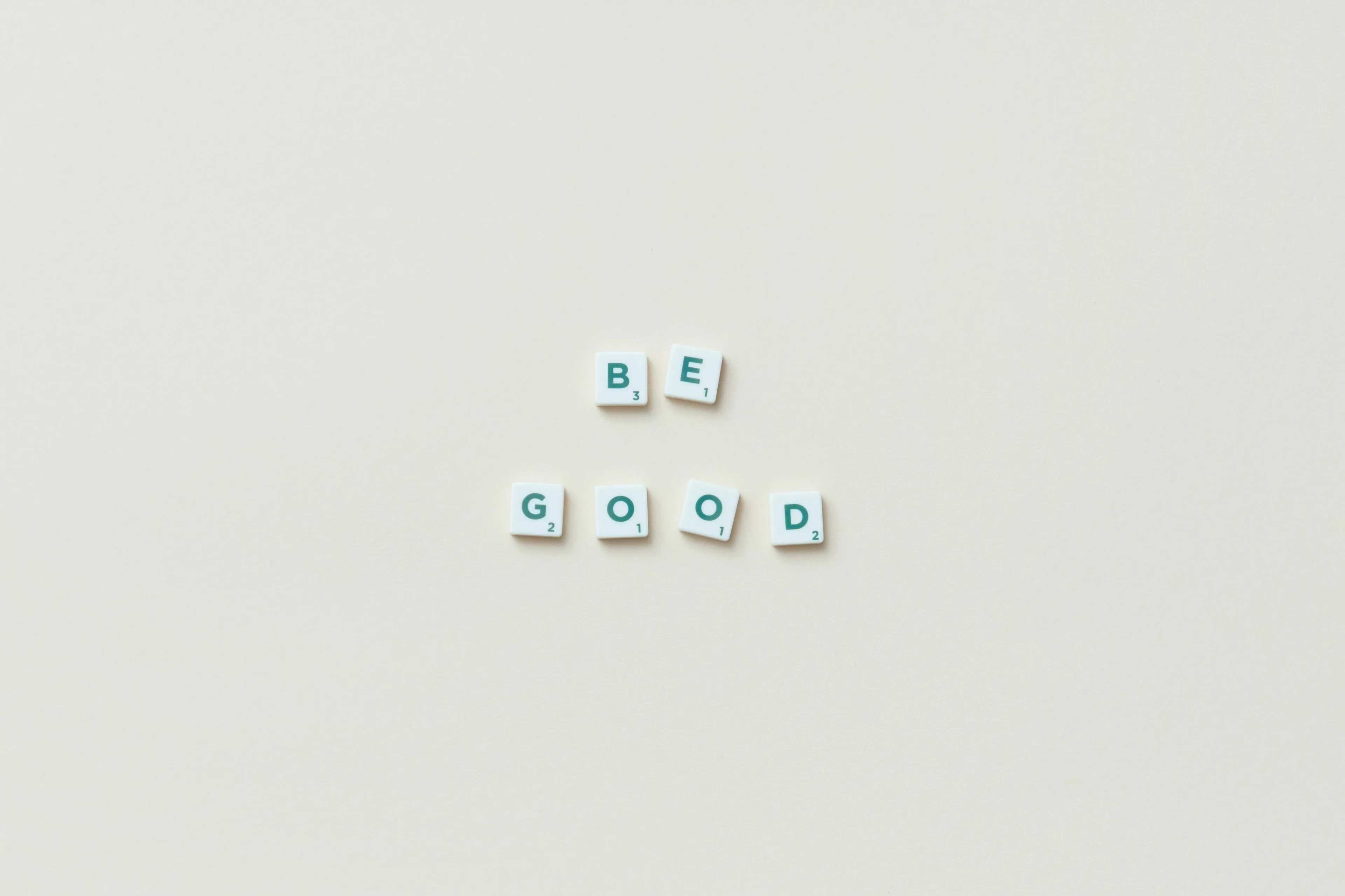 Scrabble tiles spelling out BE GOOD on a light background, representing the comparative form of the adjective good.