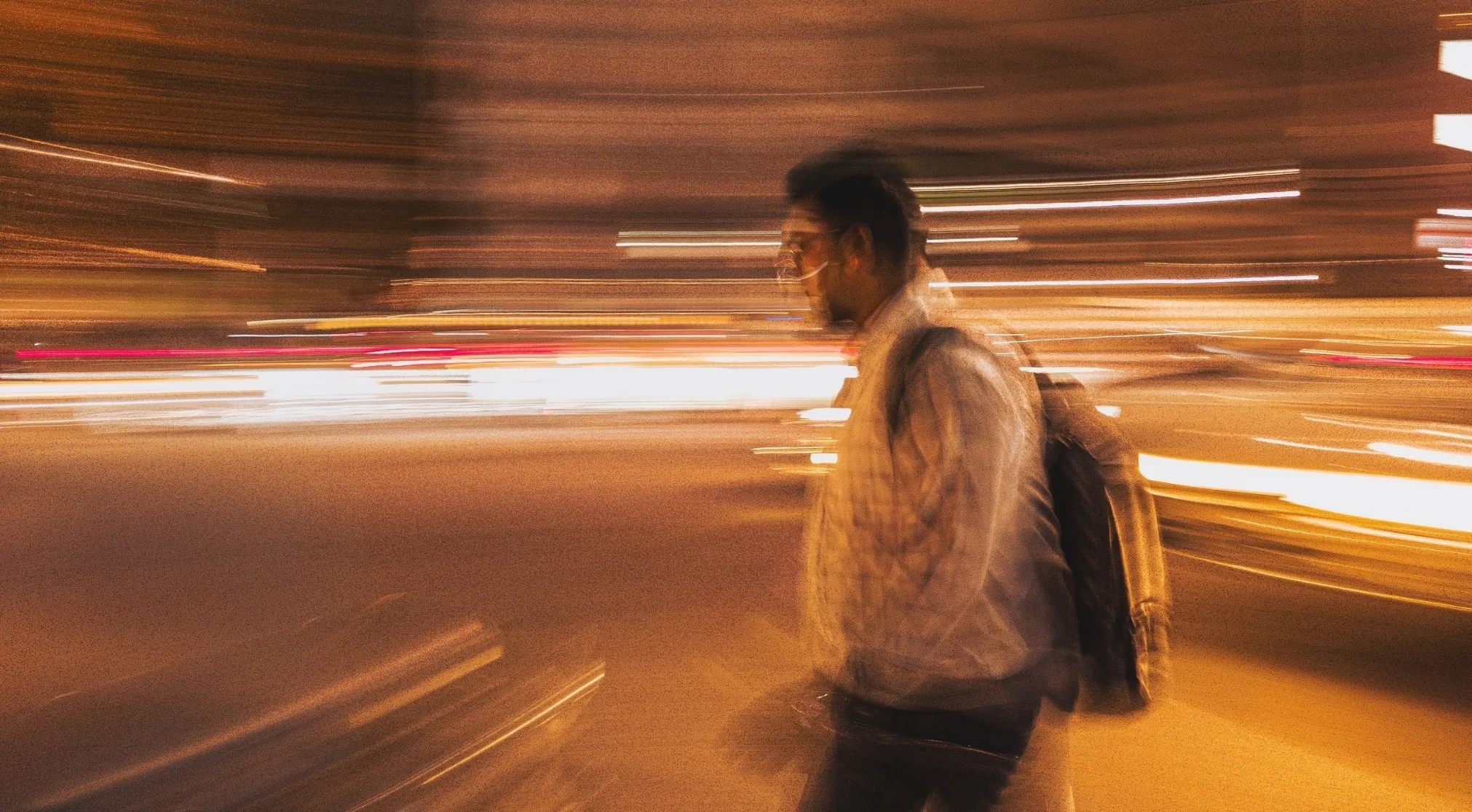 Blurred motion photo of a person walking at night, with streaks of light, related to vector quantity quiz.