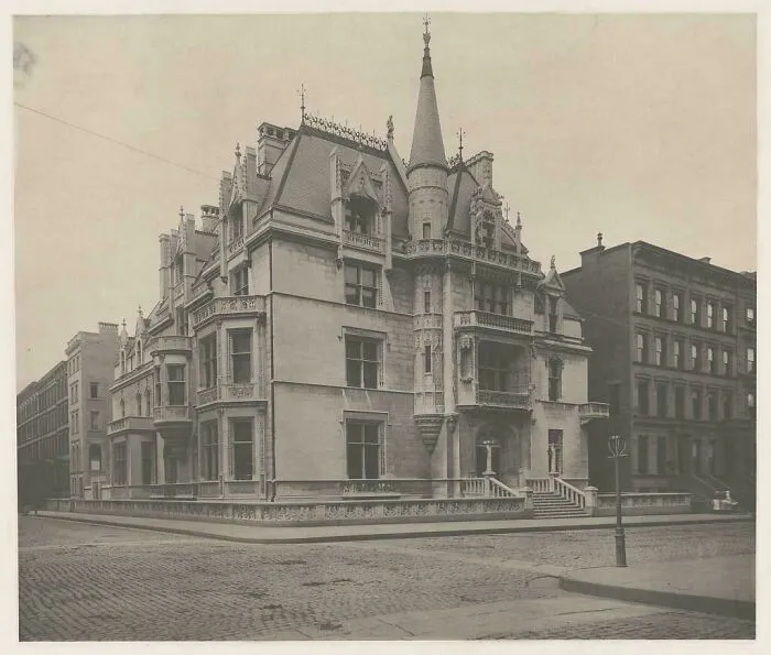 Beautiful photo from history of a grand, ornate mansion on a corner with a cobblestone street