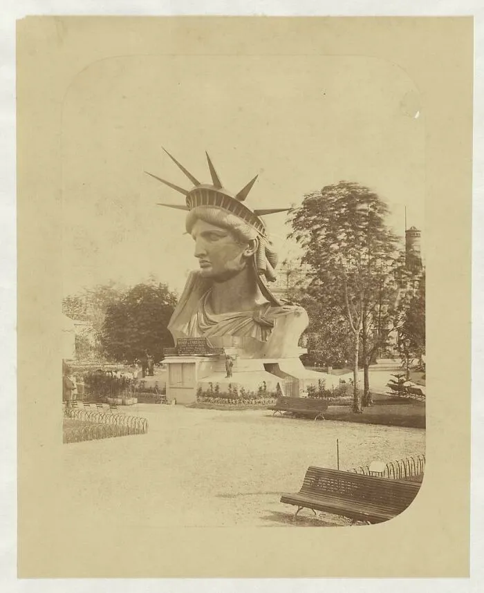 An interesting historical photo of the Statue of Liberty's head on display in a park, capturing a beautiful moment.
