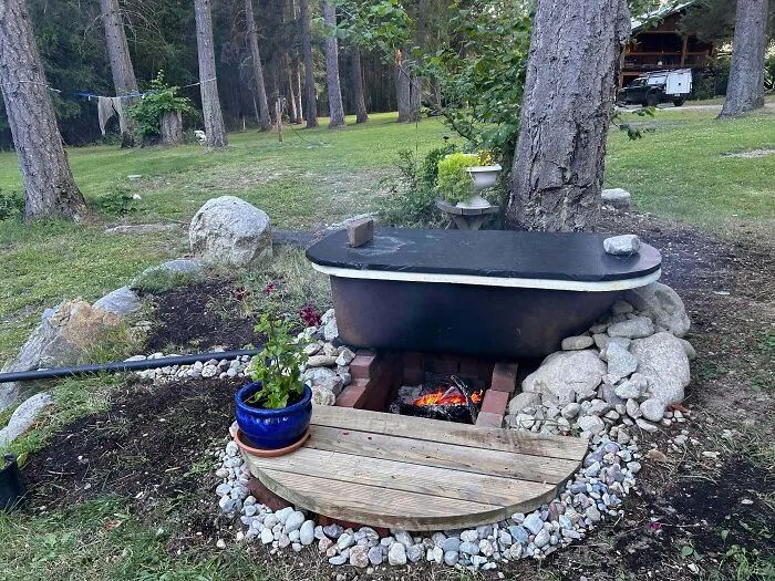 An old bathtub repurposed as an outdoor hot tub with a fire pit underneath, a clever solution.