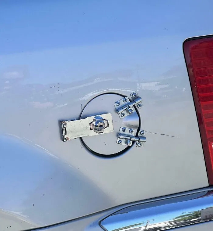 A car's fuel cap secured with multiple latches and a padlock, an inventive clever solution.