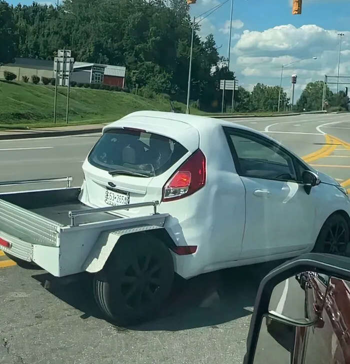 A white car converted into a pickup truck, showcasing people turning random junk into clever solutions.