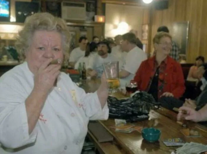 A fascinating photo from American history shows a woman with a cigar in a lively bar setting, surrounded by other patrons.