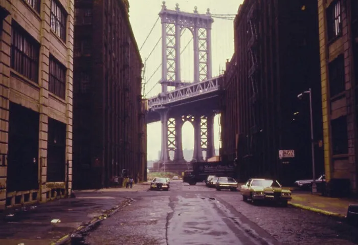 A fascinating photo from American history shows a street leading towards the iconic Manhattan Bridge, flanked by old industrial buildings.