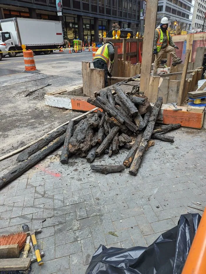Workers at a construction site revealing fascinating photos from American history, showing old wooden pipes.