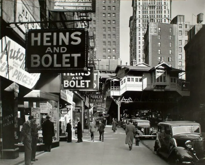 Fascinating photo of a bustling street scene with an elevated train and storefronts from American history.