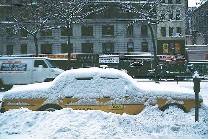 A rare photo from American history shows a yellow taxi buried in heavy snow on a city street.