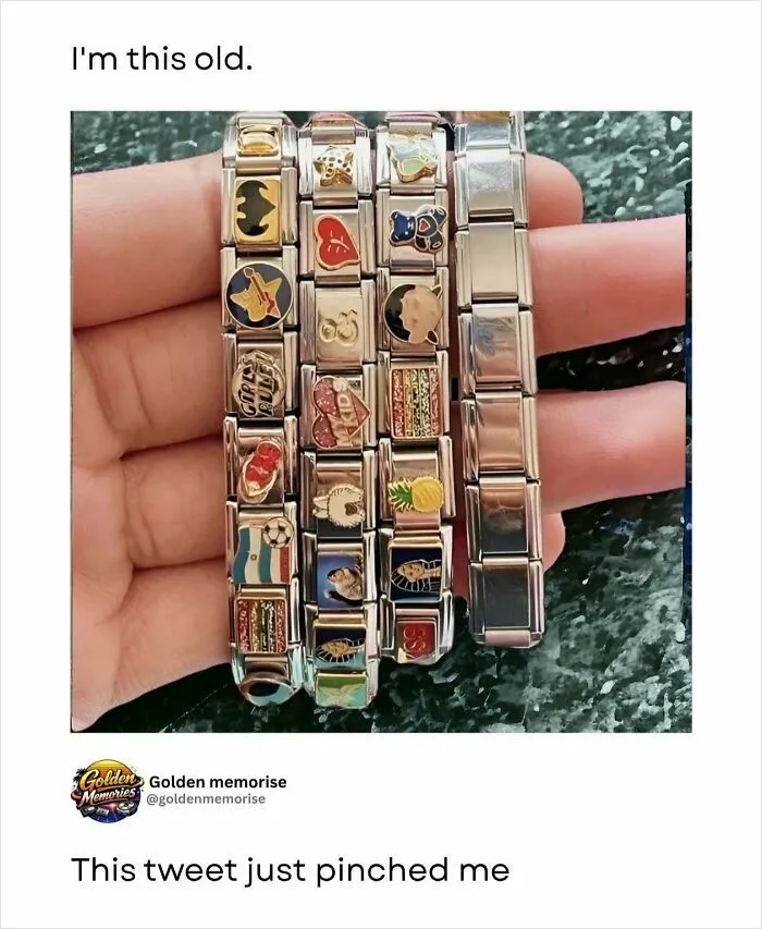 A hand holding several old-fashioned charm bracelets with various small charms, a '90s post that's so nostalgic.