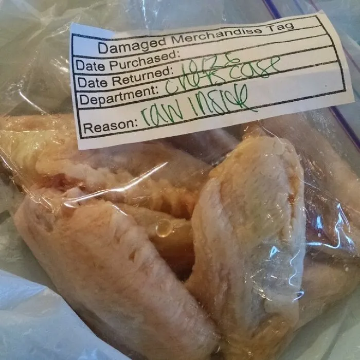 Raw chicken wings with a 'Damaged Merchandise Tag' that states the reason for return as 'raw inside,' highlighting dumb people.