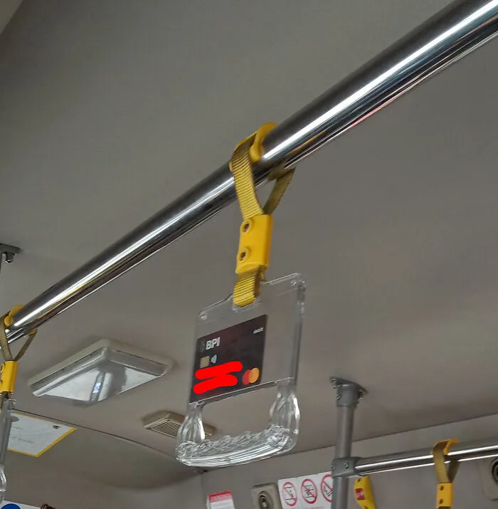 A bank card attached to a public transport handle, illustrating a dumb way to secure valuables.