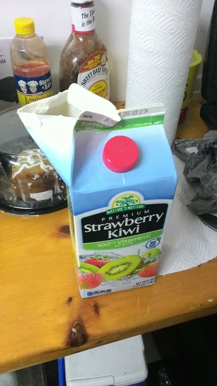 A carton of strawberry kiwi juice with the top ripped open instead of using the cap, illustrating people so dumb.