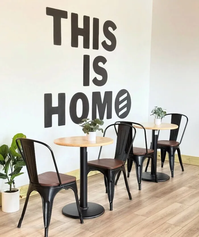 A cafe with a large wall decal reading THIS IS HOME, but the last E in HOME is reversed, showing people so dumb.