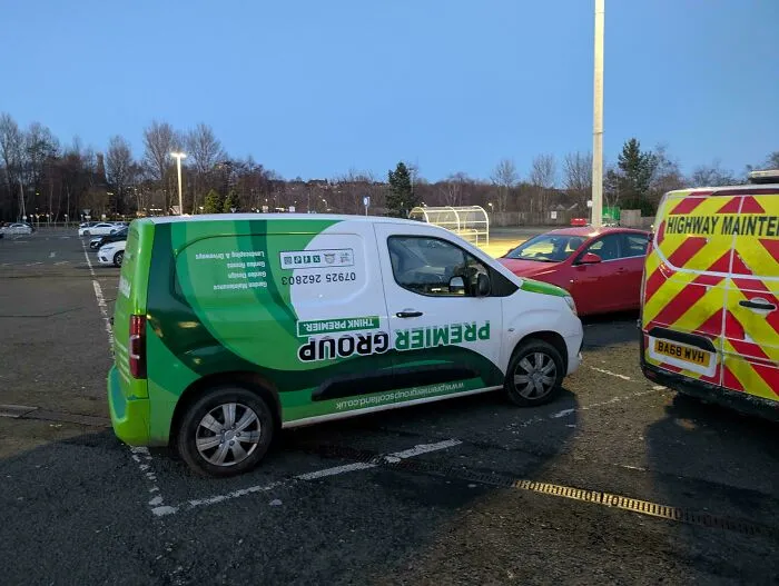 A Premier Group van parked horizontally across two spots, showing dumb parking.