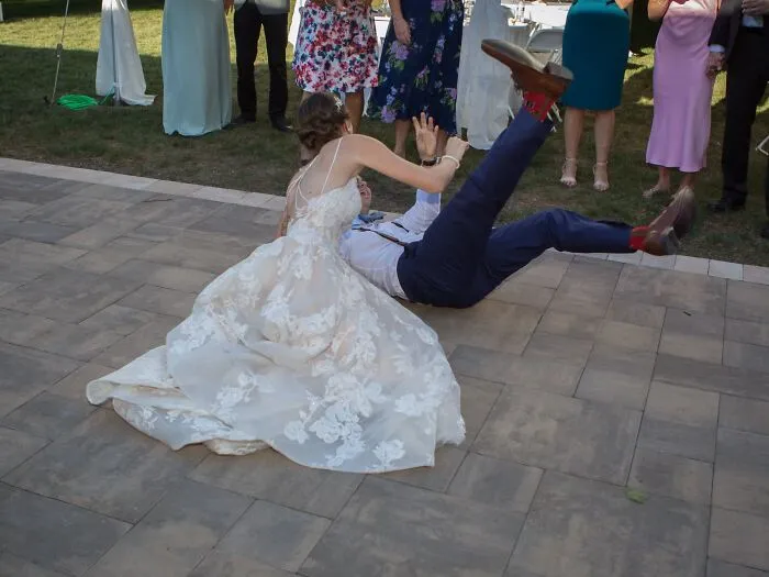Bride and groom fall while dancing, creating a funny and iconic wedding photo moment.
