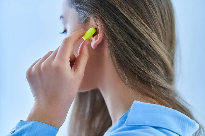 A woman inserting an earplug, demonstrating she forgot the name of something.