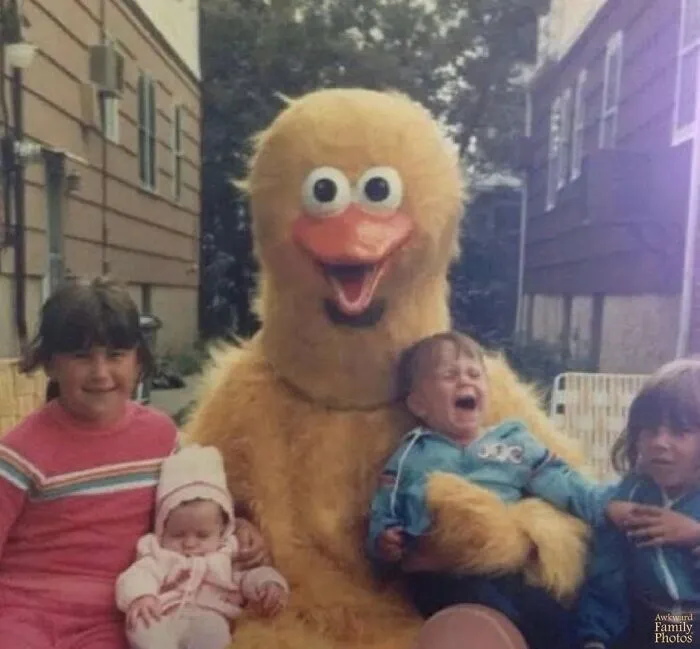 Awkward family photos: Kids meet a truly terrifying yellow character mascot, one crying and another peaceful.