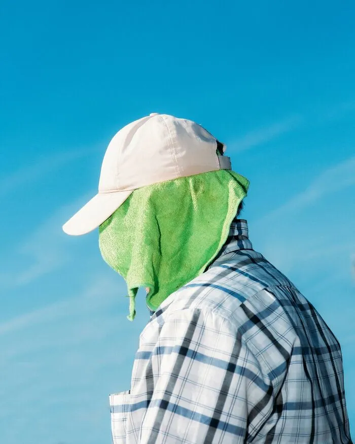 A person with a white cap and green cloth covering their face, an example of well-timed street shots.