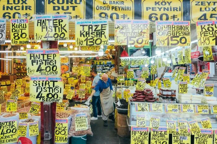 A photographer captured well-timed street shots of a bustling market with many food stalls and price signs.