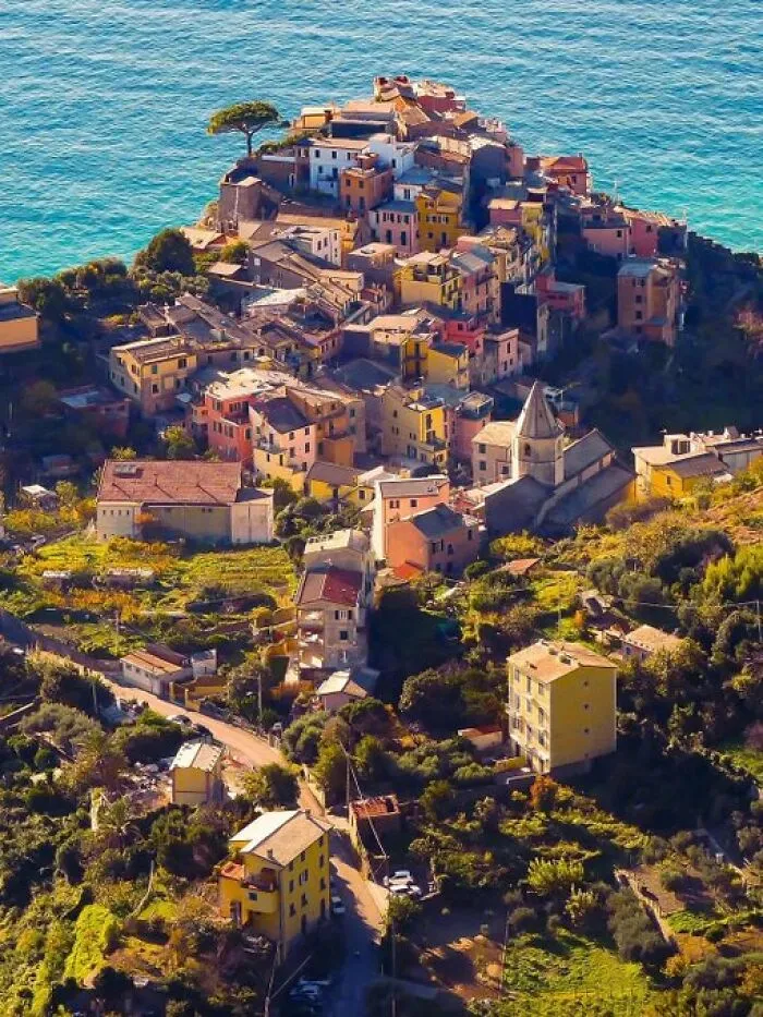 A picturesque coastal village featuring many colorful buildings cascading down a hill towards the vibrant blue sea, full of unique character.