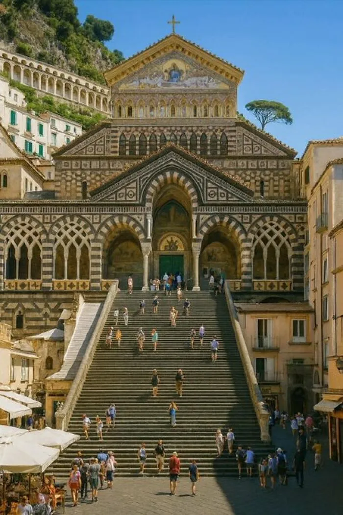 Tourists ascend a grand staircase to an ornate cathedral, an impressive building with historic architectural character.
