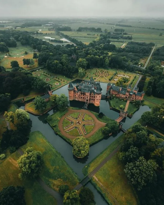 Aerial view of a stunning castle with moats and landscaped gardens, showcasing buildings with so much character.