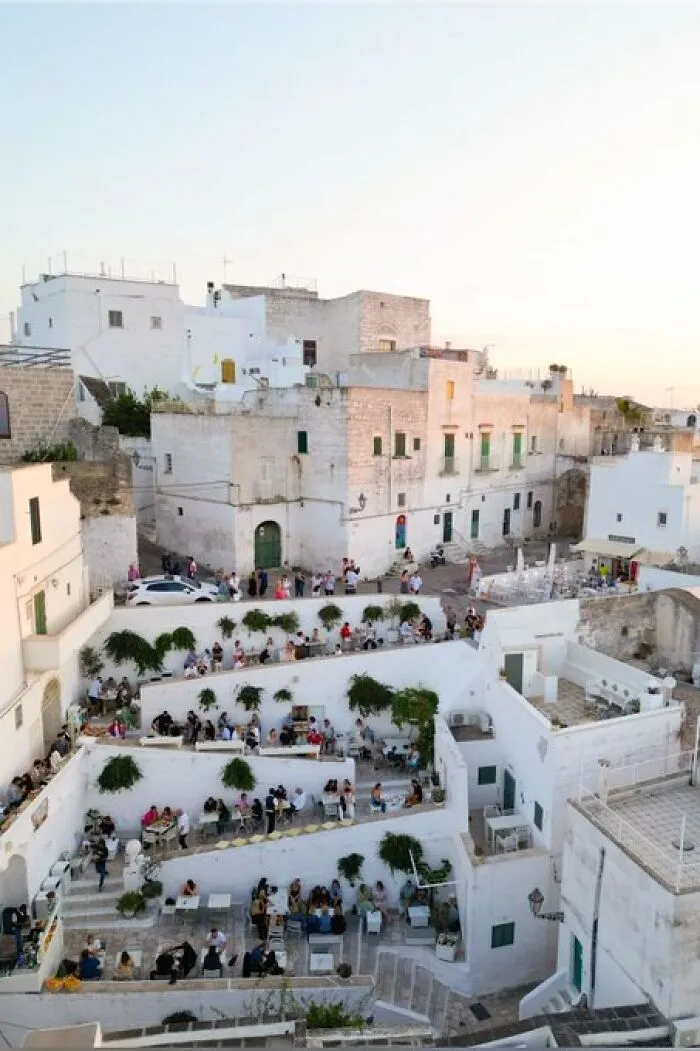 Whitewashed hillside town with outdoor dining terraces, featuring buildings with so much character and charm.