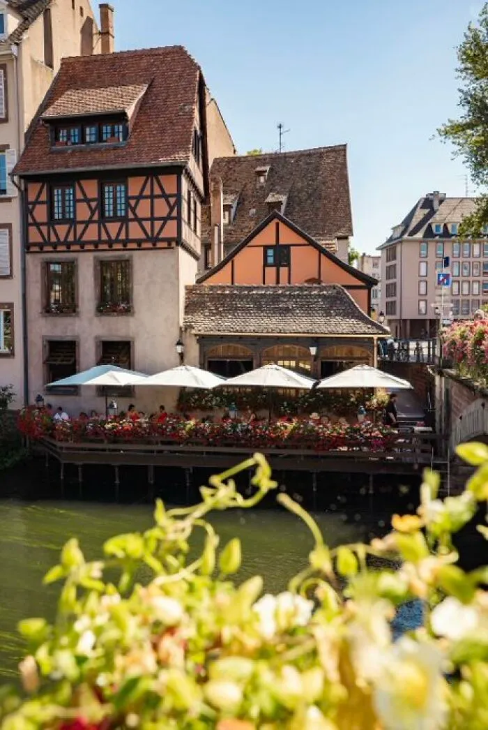 Charming, half-timbered buildings with character and a waterside restaurant patio adorned with flowers.