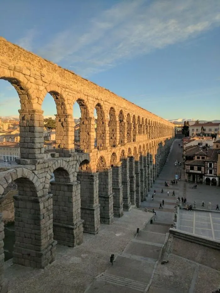 A grand ancient Roman aqueduct with numerous arches stretching across a town, an impressive building with character.