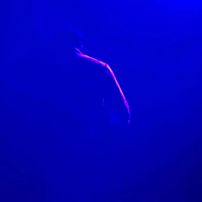 Blue-lit silhouette of a person in a minimalist photography style, emphasizing light and simplicity.