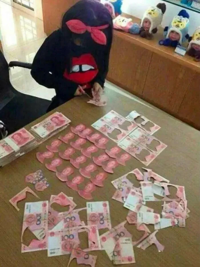 A person cutting up money on a table, an unhinged and cursed image.