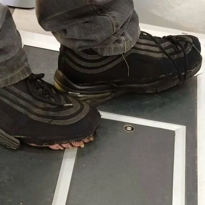 A pair of worn black sneakers with exposed toes, a cursed image of footwear.