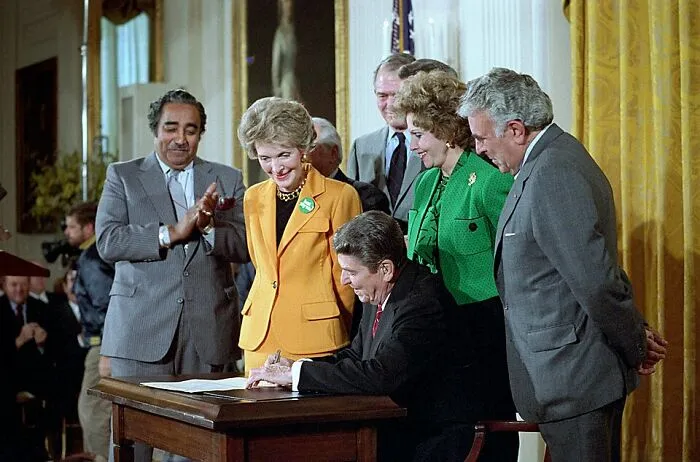 President Reagan signing a bill surrounded by officials, a fascinating photo from American history.