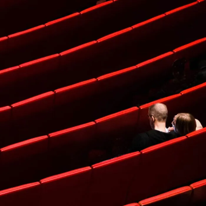 A couple sits in minimalist photography, highlighting the beauty of simplicity with red tiered seating.