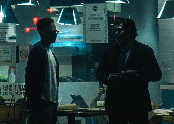 Two patrons in a dimly lit bar, possibly discussing strange things overheard by bartenders.