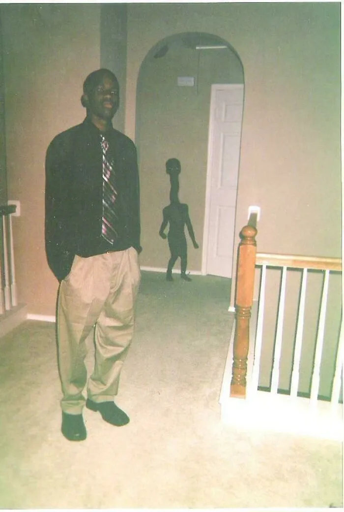 Unsettling photos of a man posing in a hallway with a creepy silhouette in the background.