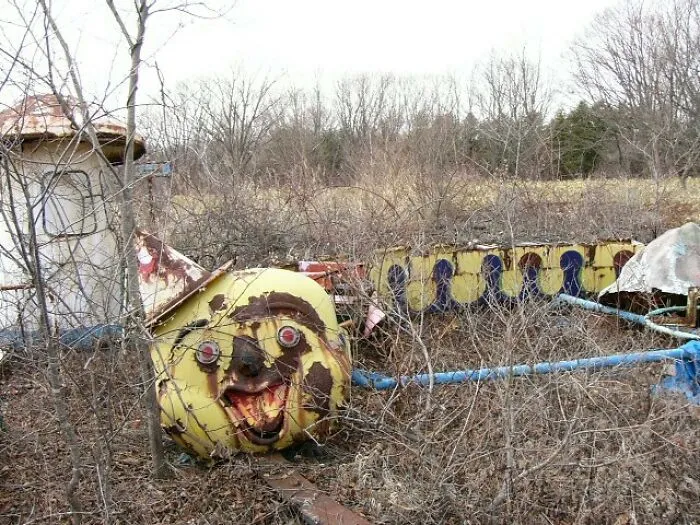 Unsettling photos and pictures of a rusted, abandoned amusement park ride resembling a clown head.