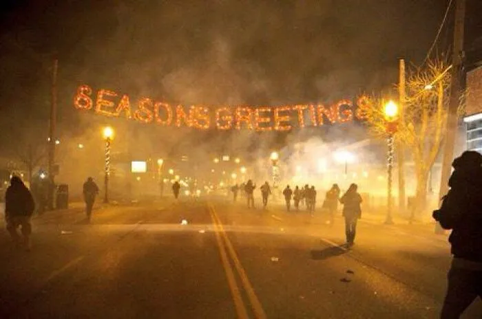 Unsettling photos: A smoke-filled street at night with an illuminated Seasons Greetings sign, a chaotic picture.