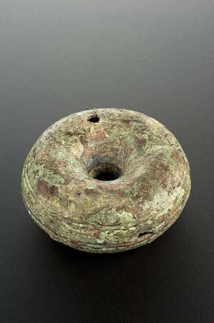 A circular, weathered artifact with a hole in the center, hinting at terrifying methods and tools doctors used in the past.