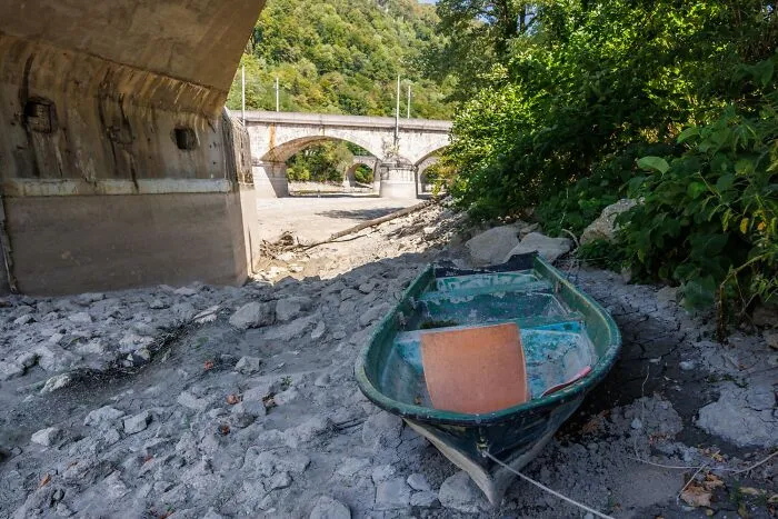 A Boat Is Seen Stranded Under A Bridge In A Mostly Dry Riverbed