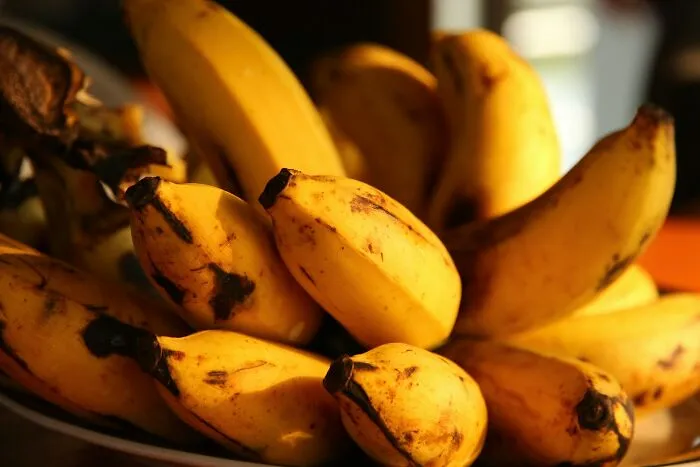 A close-up shot of a bunch of ripe bananas on a plate, some with brown spots, related to questionable Instacart shopper selections.