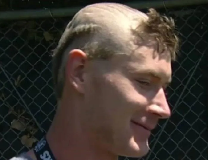 A man with a bold, partially shaved hairstyle, featuring short, spiky hair on top and a shaved back.