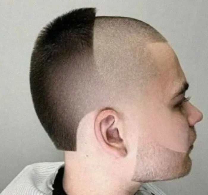 A man with a half-shaved bold hairstyle, featuring a sharp, asymmetrical line across his head.