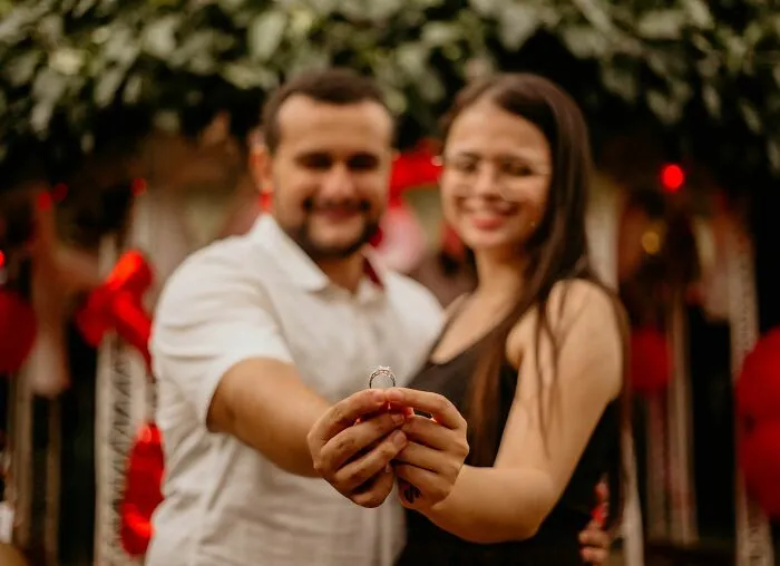 A couple holds up an engagement ring, celebrating. A firsthand witnessed moment of love, with possibly hilarious backstory.