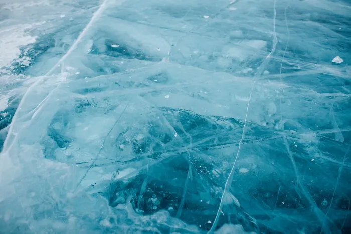 Close-up of translucent blue ice with cracks and bubbles, an absurd and hilarious firsthand texture.